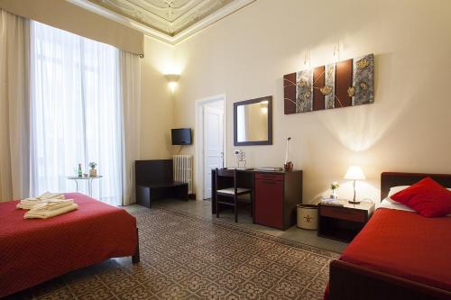 a hotel room with two beds and a desk at Antiche Volte in Catania