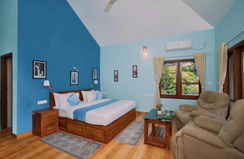 a bedroom with blue walls and a bed and a couch at Zenha Resorts in Munnar
