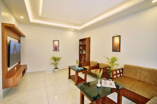 a living room with a couch and a tv at Zenha Resorts in Munnar