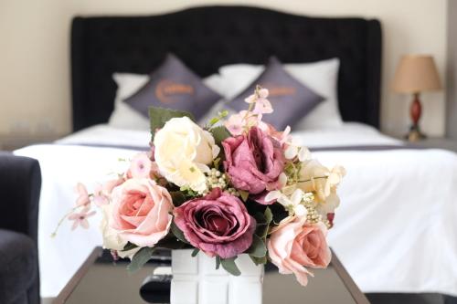 a vase filled with flowers on a table in a bedroom at Aisha HOTELS and APARTMENTS in Hanoi