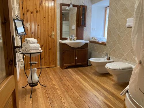 ein Badezimmer mit einem Waschbecken, einem WC und einem Spiegel in der Unterkunft B&B Maison Vallomy in Lillianes