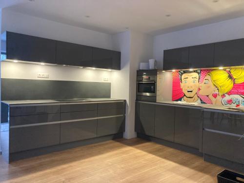 una cocina con armarios negros y una pintura en la pared en City Park Loft, en Münchberg