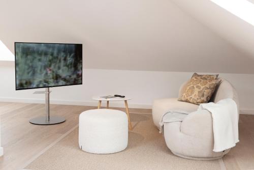 a white living room with a chair and a tv at Quartier 99 in Innsbruck