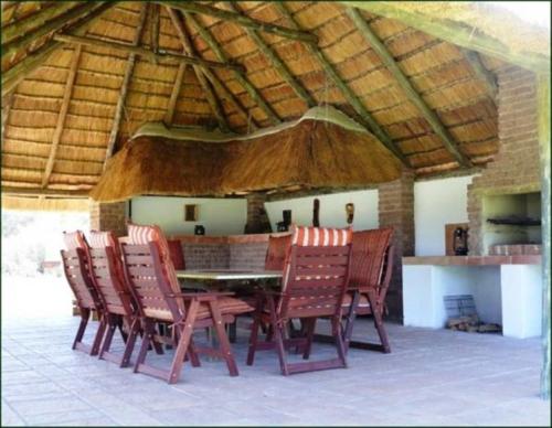 a dining room with a table and chairs under a roof at Riverbend Self Catering Cottages in Magaliesburg