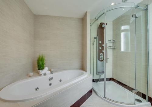 a bathroom with a tub and a glass shower at La Villa in Rottingdean