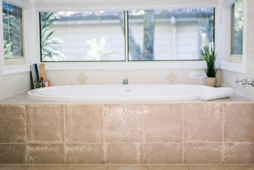 La salle de bains est pourvue d'une baignoire et d'une fenêtre. dans l'établissement Shambala Eco Retreat, à Mount Tamborine