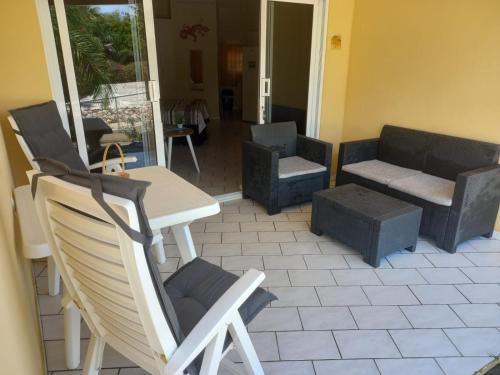 eine Terrasse mit Stühlen, einem Tisch und einem Sofa in der Unterkunft Seru Coral Resort studio 16 in Willemstad