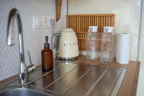 - un comptoir de cuisine avec évier et bouteilles de verre dans l'établissement Les Hirondelles, gîte de charme avec jardin, 7p, à Saint-Valery-sur-Somme