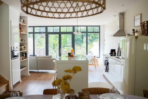 une cuisine avec des appareils blancs et une grande fenêtre dans l'établissement Les Hirondelles, gîte de charme avec jardin, 7p, à Saint-Valery-sur-Somme