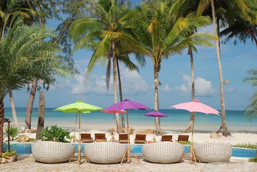a group of chairs and umbrellas on the beach at Tinkerbell Resort @ Koh Kood in Ko Kood
