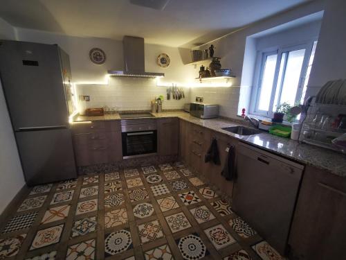 a kitchen with a tile floor with a refrigerator and a sink at La Casa de los Pájaros in Vélez Blanco