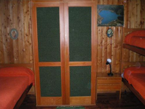 スカンノにあるResidence I Comignoliのベッド2台と木製のドアが備わる客室です。