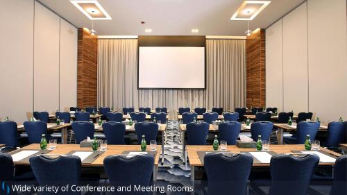 a conference room with tables and chairs and a projection screen at Grand Cosmopolitan Hotel in Dubai