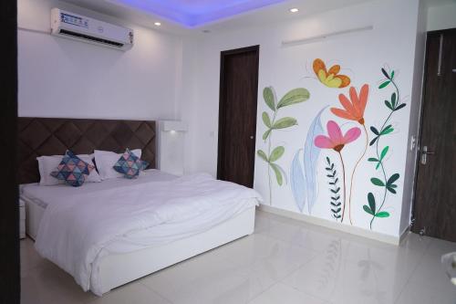 1 dormitorio con 1 cama con un mural de flores en la pared en Own Stay, en Nueva Delhi