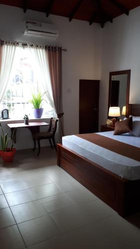 a bedroom with a bed and a desk and a window at Jal,Min Homestay in Kandy