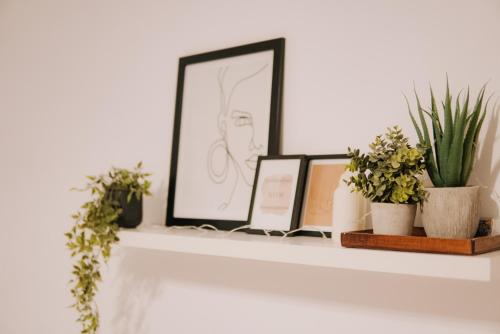 a white shelf with plants and pictures on it at Cozy 2-Bedroom Boho-Themed Home in Caransebeş
