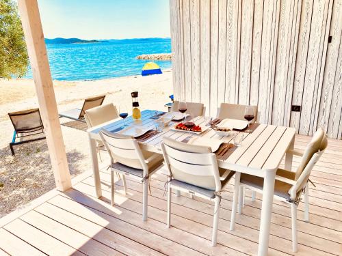 uma mesa branca e cadeiras num deque com praia em BUQEZ ECO RESORT - Beach Villa 28 - Directly by beach em Drage