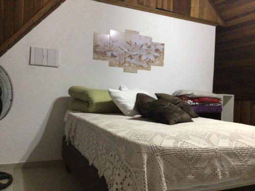 Bett in einem Zimmer mit zwei Bildern an der Wand in der Unterkunft Espaço Jardim Curitiba in Curitiba