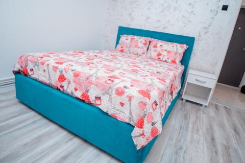 un letto blu con piumino e cuscini rossi e bianchi di Studio Salin a Turda