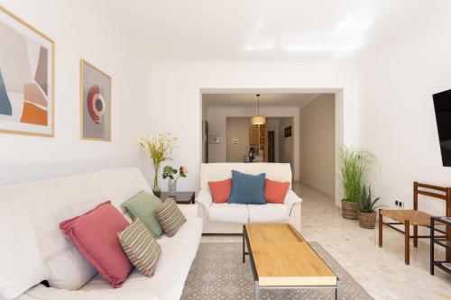 ein Wohnzimmer mit einer weißen Couch mit bunten Kissen in der Unterkunft Marina 8 - Vivienda vacacional en el corazón del Puerto De la Cruz in Puerto de la Cruz