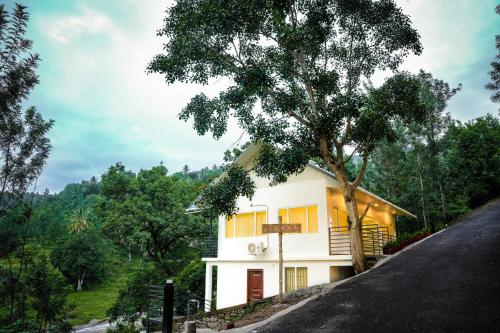 a house on the side of a hill with a tree at Misty Range Resorts in Maraiyūr