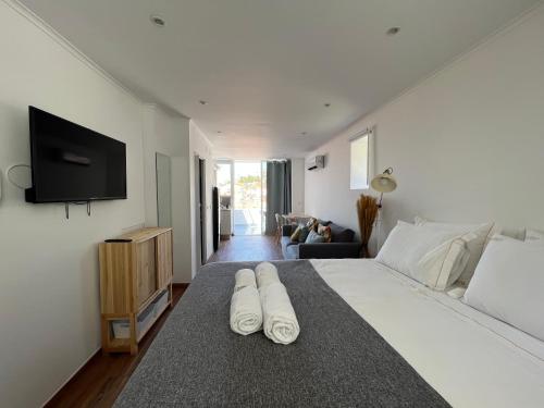 a bedroom with a large white bed with a flat screen tv at Castello Prime Suites in Lisbon