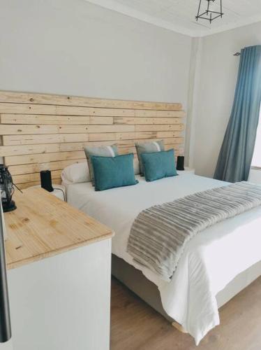 Un dormitorio con una gran cama blanca con almohadas azules. en River Cabin, en Roodepoort