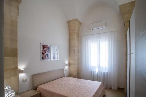 um pequeno quarto com uma cama e uma janela em La Volta - Casa Vacanze em Galatina