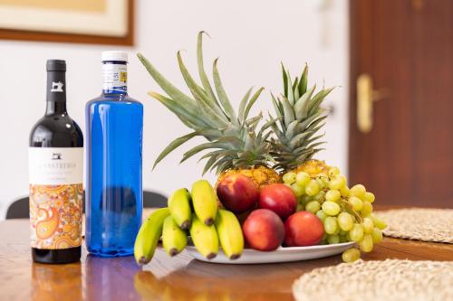 einen Obstteller auf einem Tisch neben einer Flasche Wein in der Unterkunft Marina 8 - Vivienda vacacional en el corazón del Puerto De la Cruz in Puerto de la Cruz