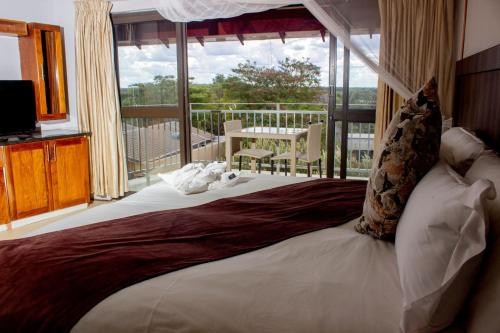 a bedroom with a large bed with a balcony at Wild View Resort in Kasane