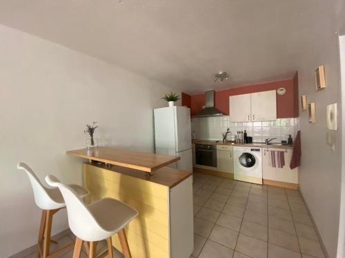 a kitchen with a white refrigerator and a table and chairs at Centre ville, parking privé in Perpignan