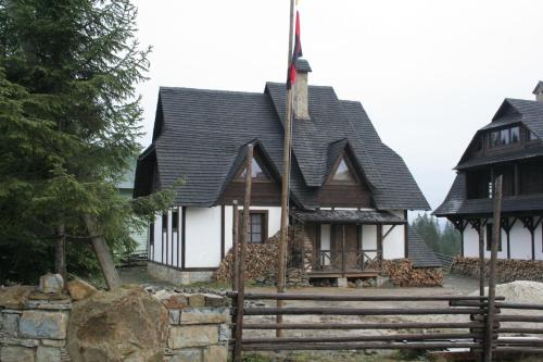 a house with a black roof and a fence at Blyzhche Neba in Yablunytsya