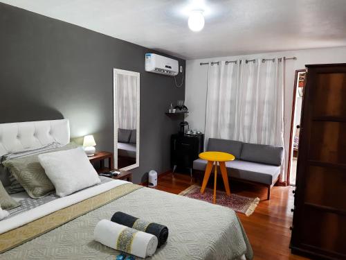 a bedroom with a bed and a couch and a table at Agellum Bed & Breakfast in Domingos Martins