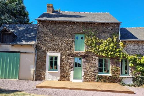 a stone house with green doors and a garage at Longère indépendante avec terrain de tennis privé in Saint-Maugan