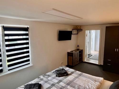 Schlafzimmer mit einem Bett, einem TV und einem Fenster in der Unterkunft Gästezimmer Teltow in Teltow