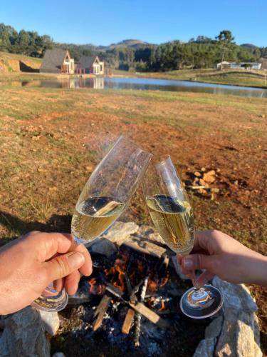 two people holding wine glasses over a campfire at Recanto Entre Rios in Bom Jardim da Serra