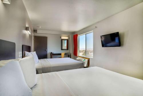 a hotel room with two beds and a tv at Motel 6-Hesperia, CA - West Main Street I-15 in Hesperia