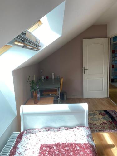 a attic room with a bed and a table at CHEZ HUSNA in Conflans-Sainte-Honorine
