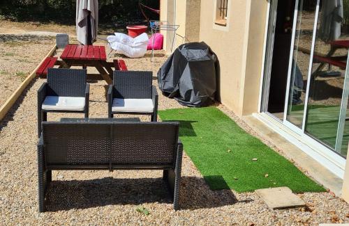 a patio with two chairs and a patch of grass at La- ch'tite-Gamassette in Carlucet