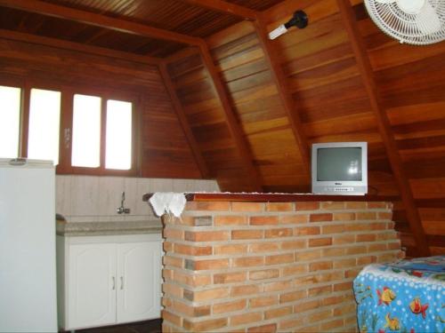 a living room with a tv on a brick wall at Chalès em Ilhabela Litoral Norte in Ilhabela