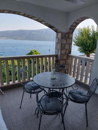 a table and chairs on a balcony with a view of the water at Apartmani Mustur in Bijela