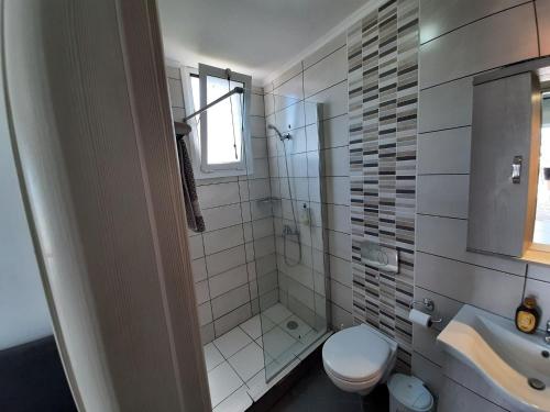 a white bathroom with a toilet and a sink at Apartment in Mpenitses with Sea Views & Pool in Benitses