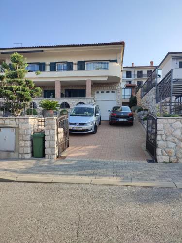 two cars parked in a parking lot in front of a house at Biuk Apartments in Novi Vinodolski
