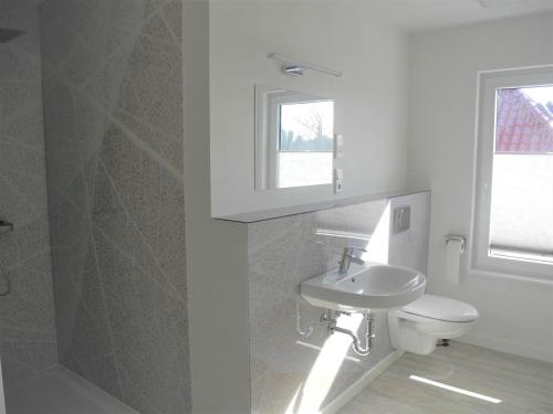 La salle de bains est pourvue d'un lavabo, de toilettes et d'une fenêtre. dans l'établissement Strandappartement Steinberghaff "zur Birk" mit Meerblick, à Steinberg