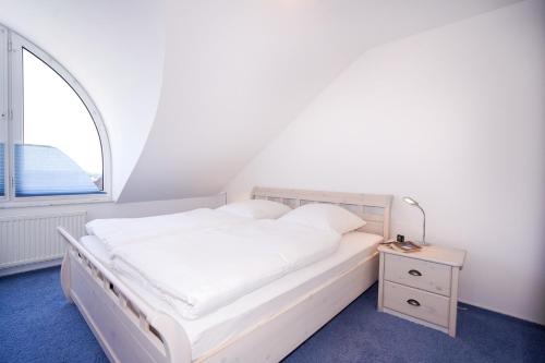 ein weißes Bett in einem Zimmer mit Fenster in der Unterkunft Haus Atlantic Whg "Ferijentied" in Grömitz