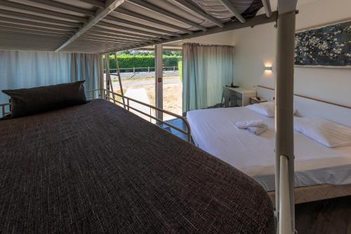 Saint-Aignan-de-CramesnilにあるLa Jalousieのベッドルーム1室(ベッド2台付)、バルコニーが備わります。