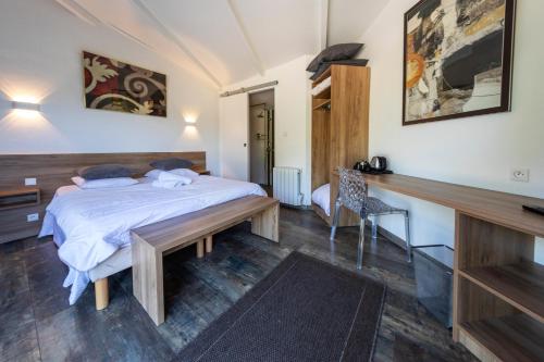 a bedroom with a bed and a wooden desk at La Jalousie in Saint-Aignan-de-Cramesnil