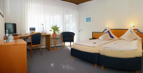 a hotel room with a bed and a desk with a computer at Landhotel Sonnenbühl in Sonnenbühl