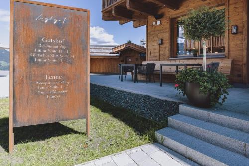 a sign in front of a house with a table at ZAGLGUT HOTEL-CHALETS Wellness & Views with Summer Card Included in Kaprun
