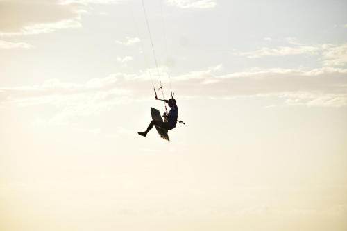a man is hanging from a parachute in the sky at Pousada farol in Areia Branca
